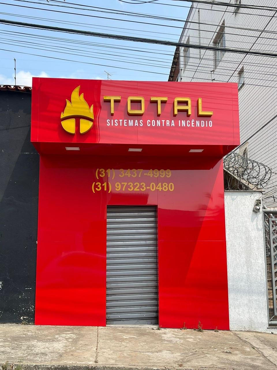 Fachada vermelha da Total Sistemas Contra Incêndio com letras em destaque.