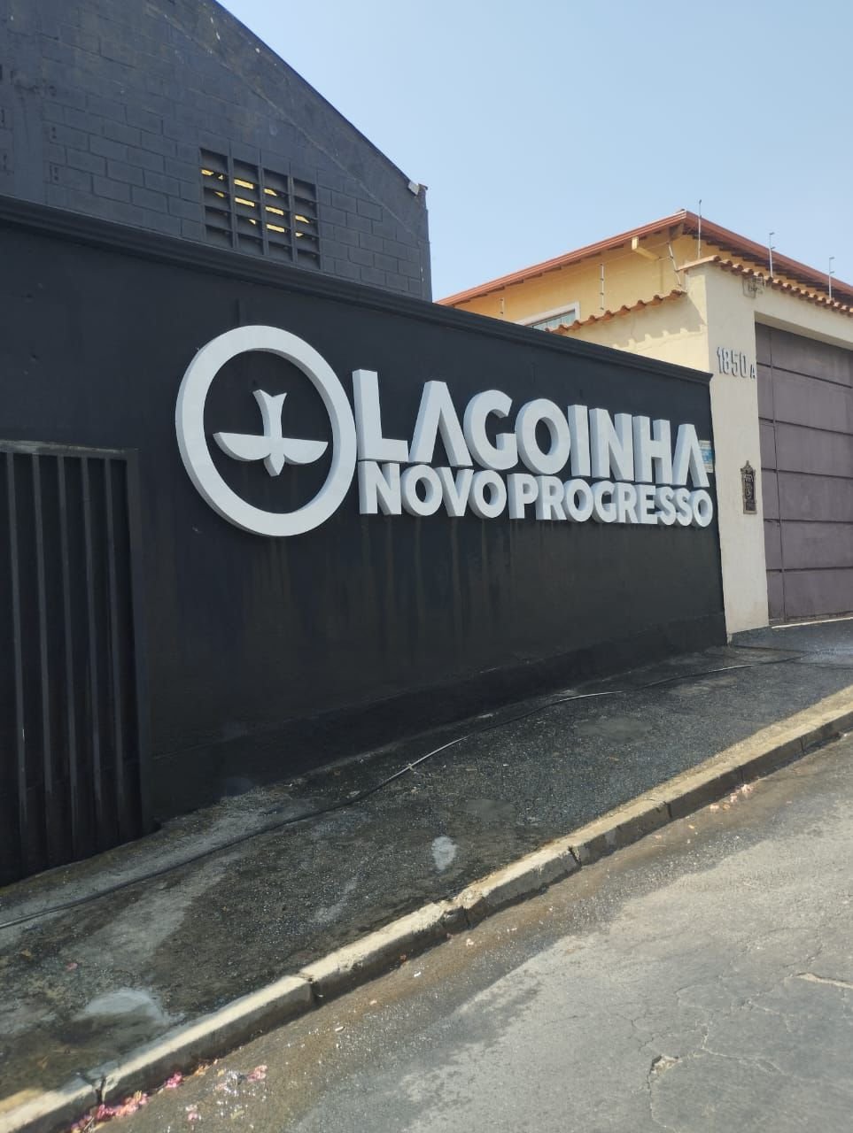 Letreiro externo da Lagoinha Novo Progresso em letras brancas sobre muro preto.